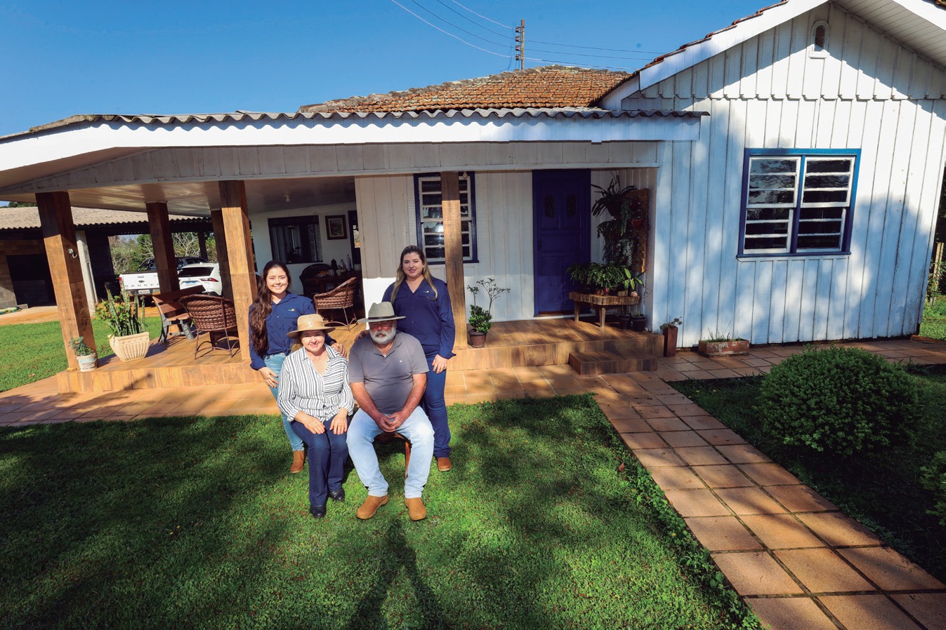 Laís e Beatriz com os pais em frente à casa da propriedade da família