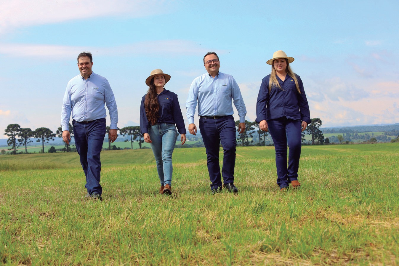 Laís e Beatriz caminhando pela propriedade ao lado de dois representantes da Coamo