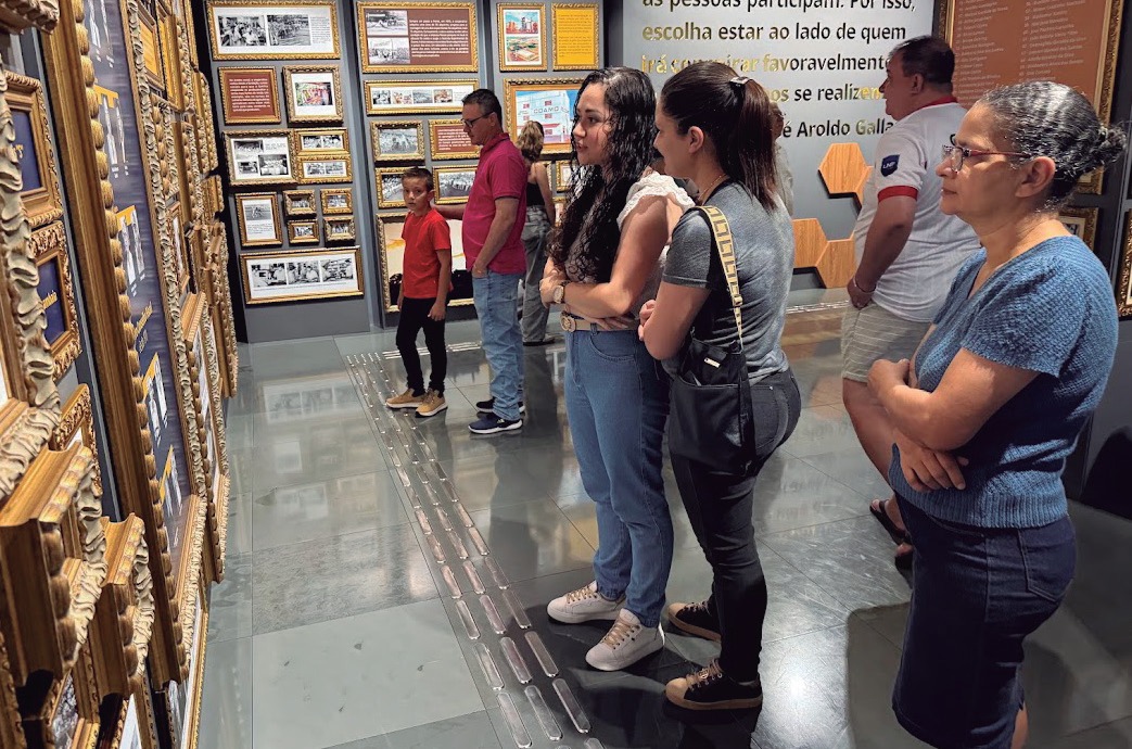 Grupo observa painel de fotos e documentos históricos no Memorial Coamo