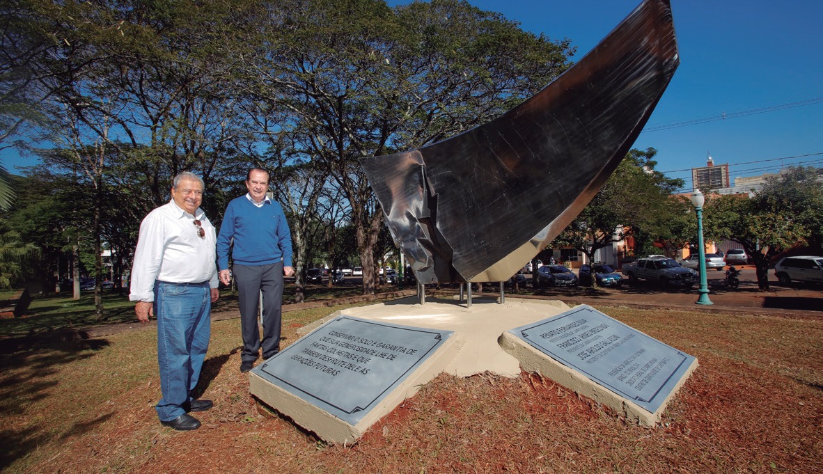 Dois homens ao lado do Monumento de Conserva&ccedil;&atilde;o do Solo, em Campo Mour&atilde;o