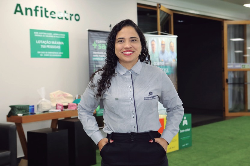 Ana Brito sorrindo diante de painel do anfiteatro