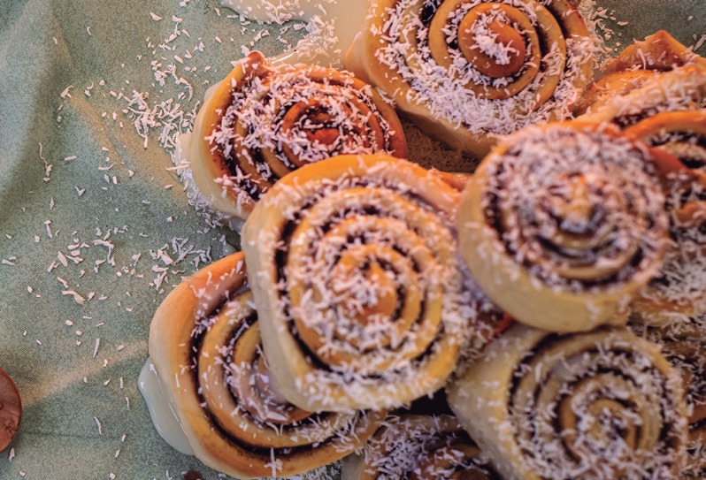 Cinnamon rolls assados com recheio de canela em espiral, cobertos com coco ralado
