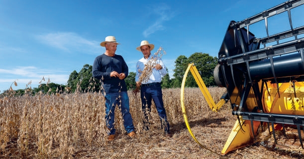 Cooperado Neri Kliemann com o agr&ocirc;nomo Marcelo Pereira perto da colheitadeira em atividade
