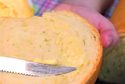 Fatia de p&atilde;o sendo untada com margarina