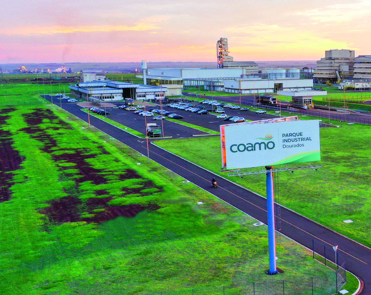 Vista a&eacute;rea do parque industrial da Coamo em Dourados, com um grande outdoor da Coamo em primeiro plano.